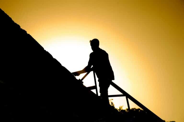 A roofer works on a roof in silhouette for Roofing Contractor in Fort Lauderdale
